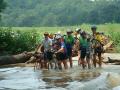 Mike Pitt (left) and Bill Pustow (second from left) and others, with bikes aloft, gingerly walk around the driftwood and across the swift-running Salt River at the flooded low culvert on Drydock Road in Anderson County.